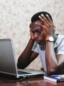 Confused man sitting at his laptop holding his head